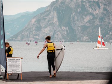 Due allievi con il salvagente portano la tavola verso il lago